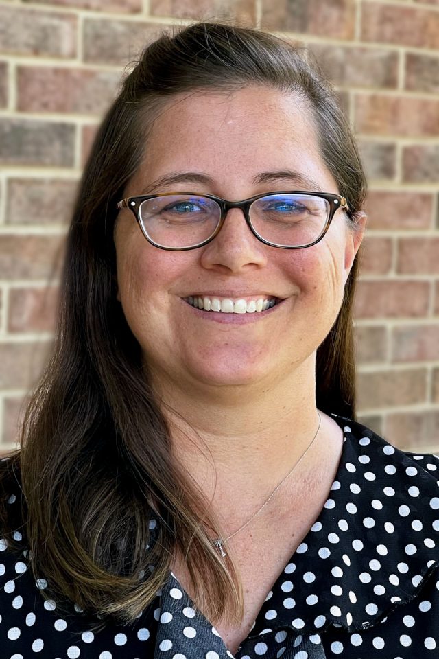 Head shot of Amber Thomasson in white polka dot blouse smiling