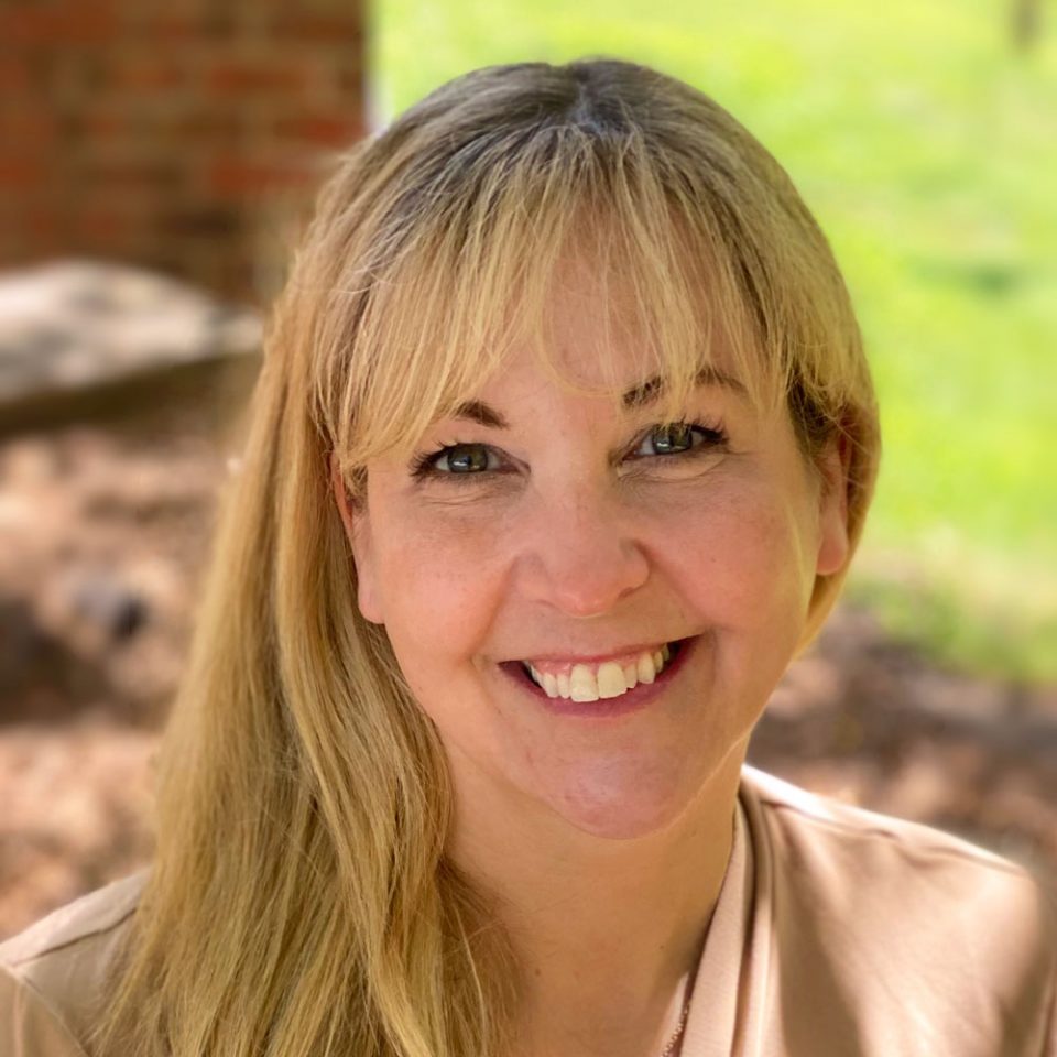 Beth Ann Scruggs director of Renew smiling into camera with long blonde hair wearing camel colored sweater over leopard print top