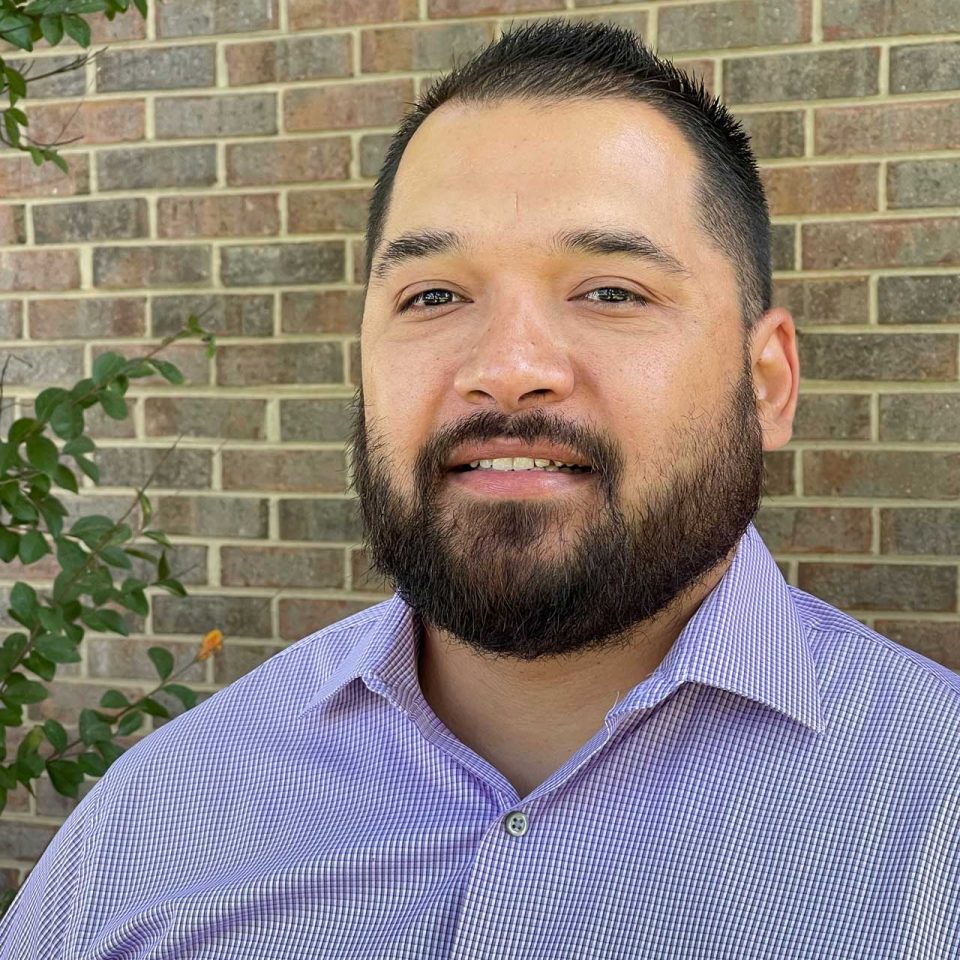 Director of Inclusion Fredy Pabon smiling in blue collared shirt