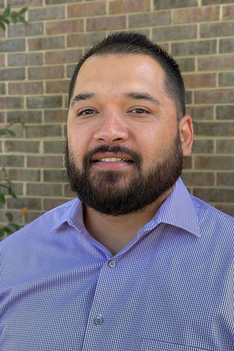 Director of Inclusion Fredy Pabon smiling in blue collared shirt