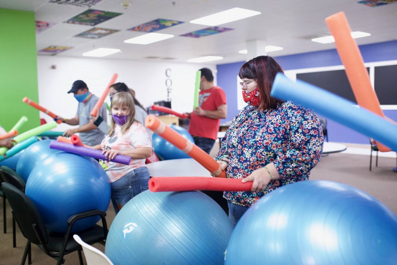 Members of the High5 day program for adults with disabilities hold brightly colored pool noodles