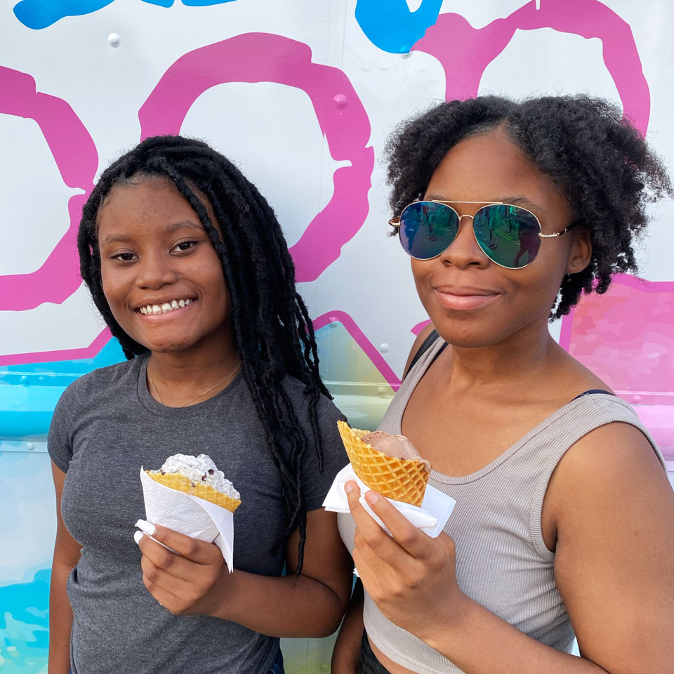 Two young girls smiling with ice cream cones from Daily SCOOPS ice cream truck