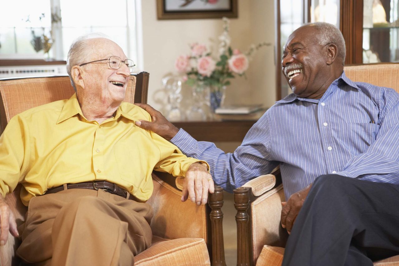 Two jovial elderly men reclining in velvet upholstered chairs