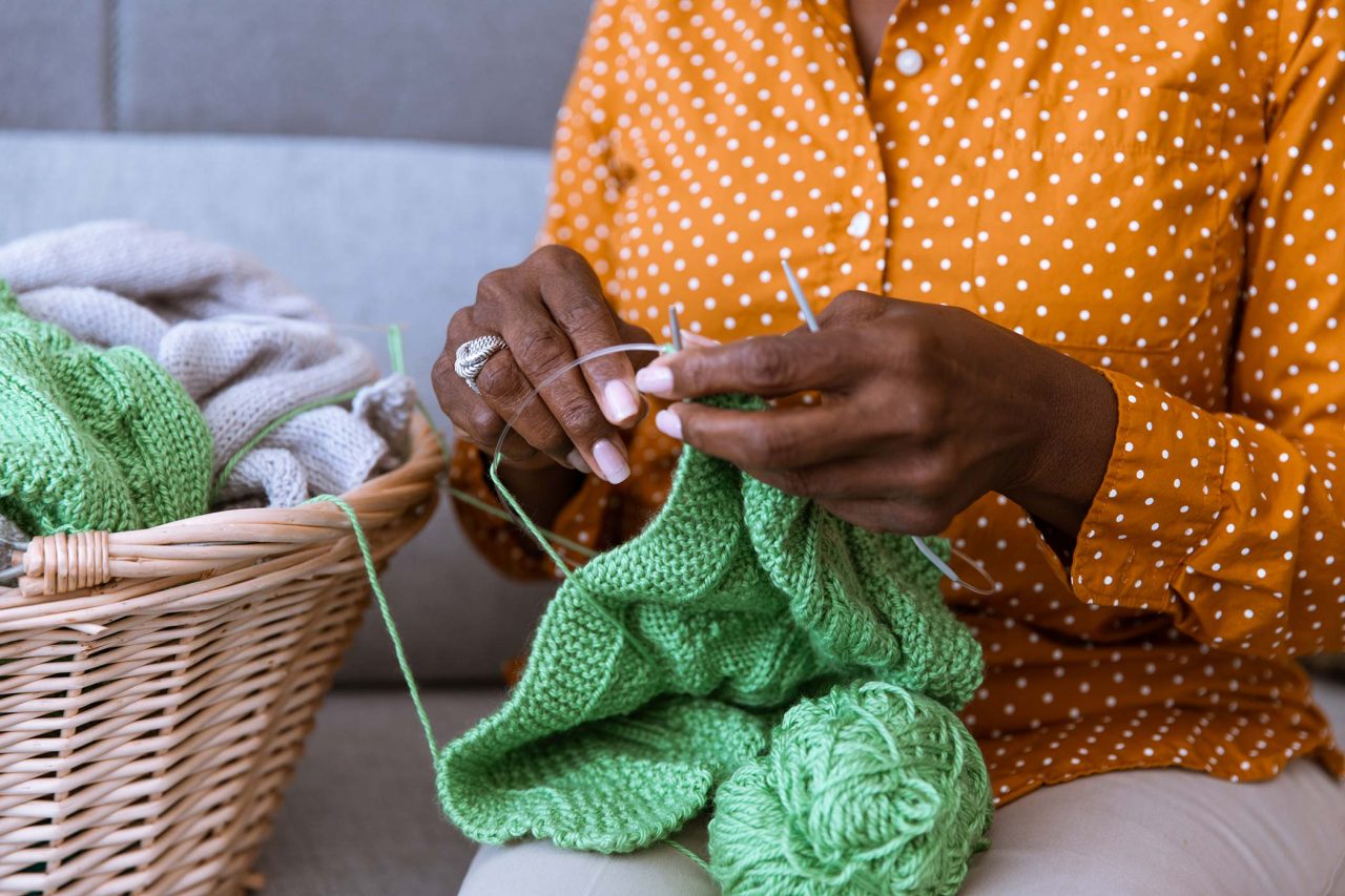 Hands knitting green yarn
