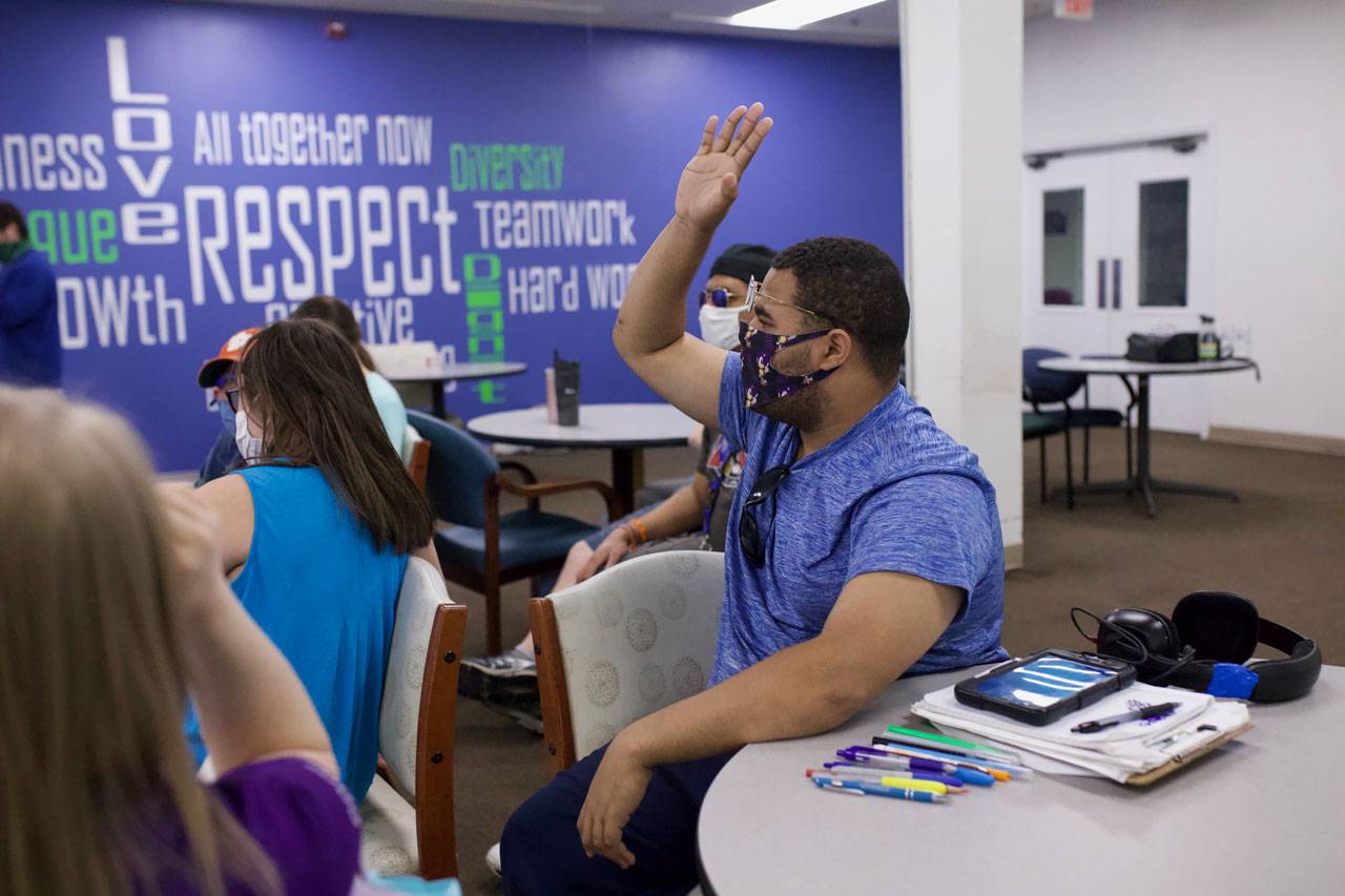 Member of the High5 day program for adults with disabilities raising hand